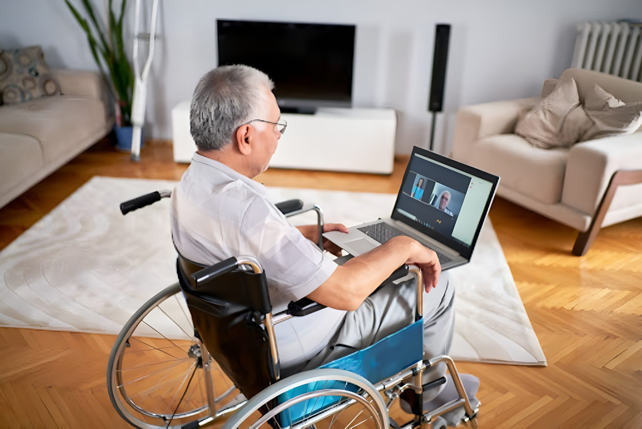  Person in wheelchair, using laptop in a home setting.